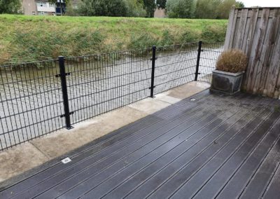 DSM hekwerk op voetplaten op terras aan rand van een water.