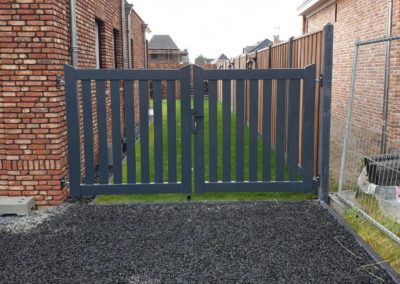 Dubbele brede spijlen poort tussen muur en hout beton schutting.