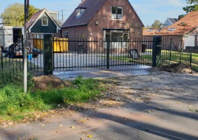 Dubbele draaipoort Adidas met brievenbus in zijstijl en naast poort hekwerk en hanenkam zijaanzicht