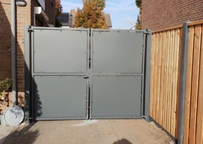 Dubbele draaipoort met dichte platen grijs naast hout beton schutting achteraanzicht